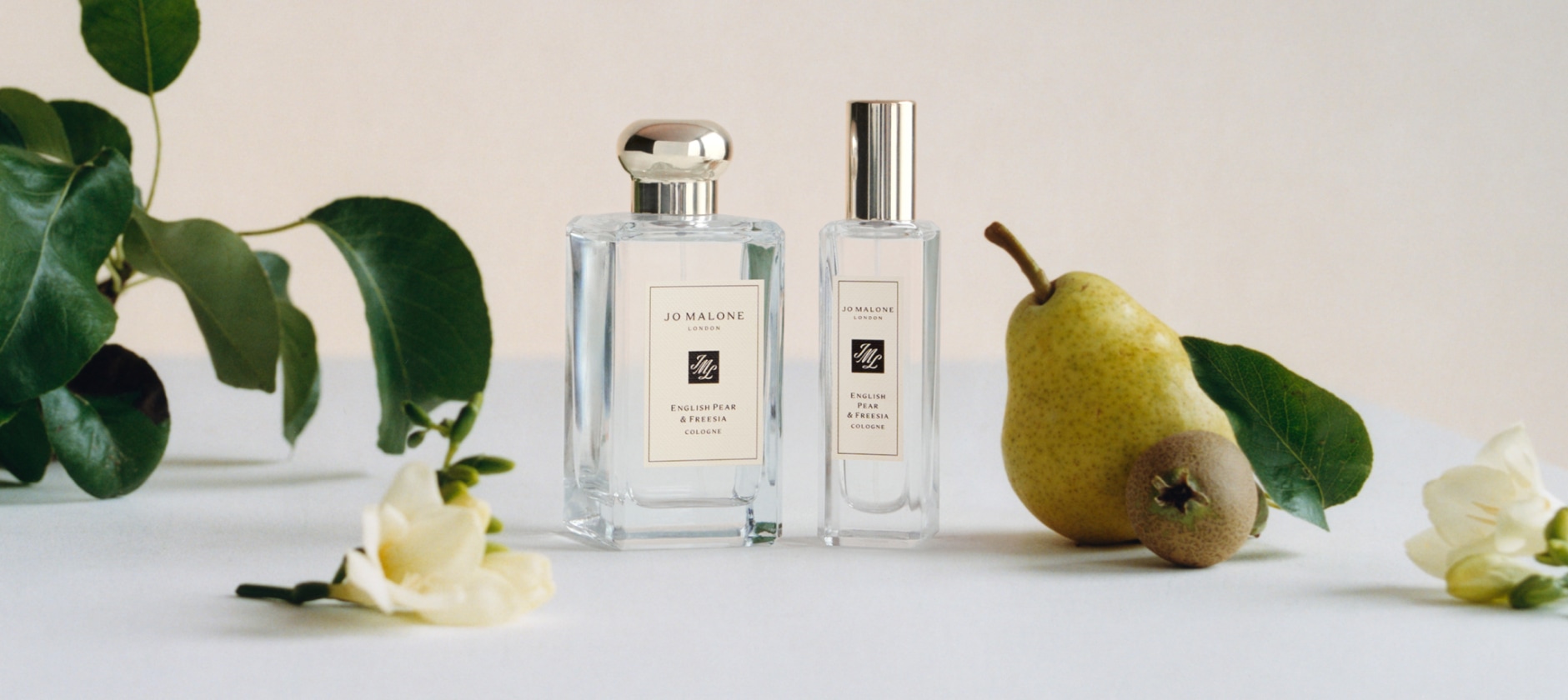 Adwoa Aboah with braided hair, biting into a pear with backdrop of three large pear props placed on top of a car roof rack.